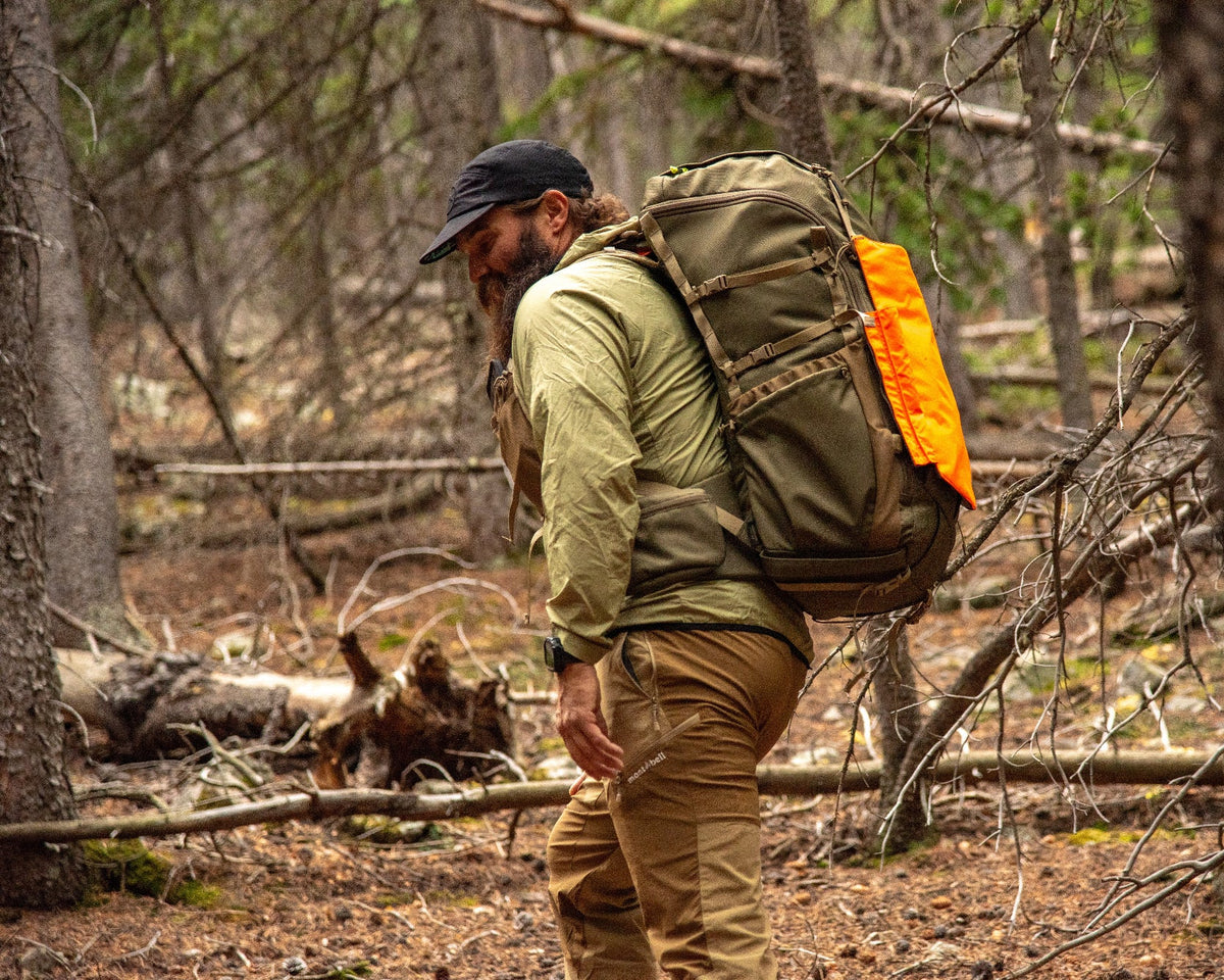 Man with beard in the woods wearing a green 45L backpack navigating forest floor deadfall