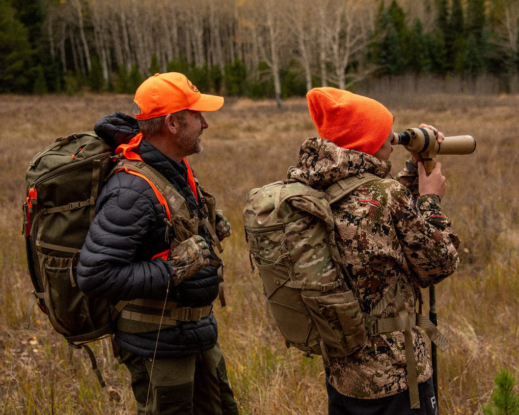 Father &amp; son using a spotting scope attached to a trekking pole in a high altitude Rocky Mountain field